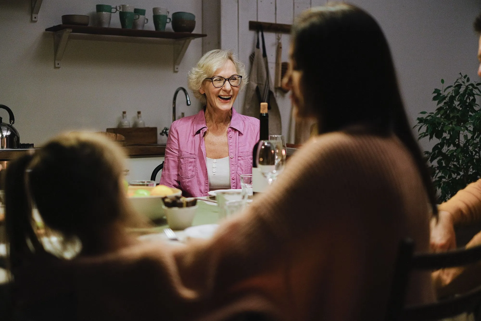 A grandmother laughing with family members around the dinner table