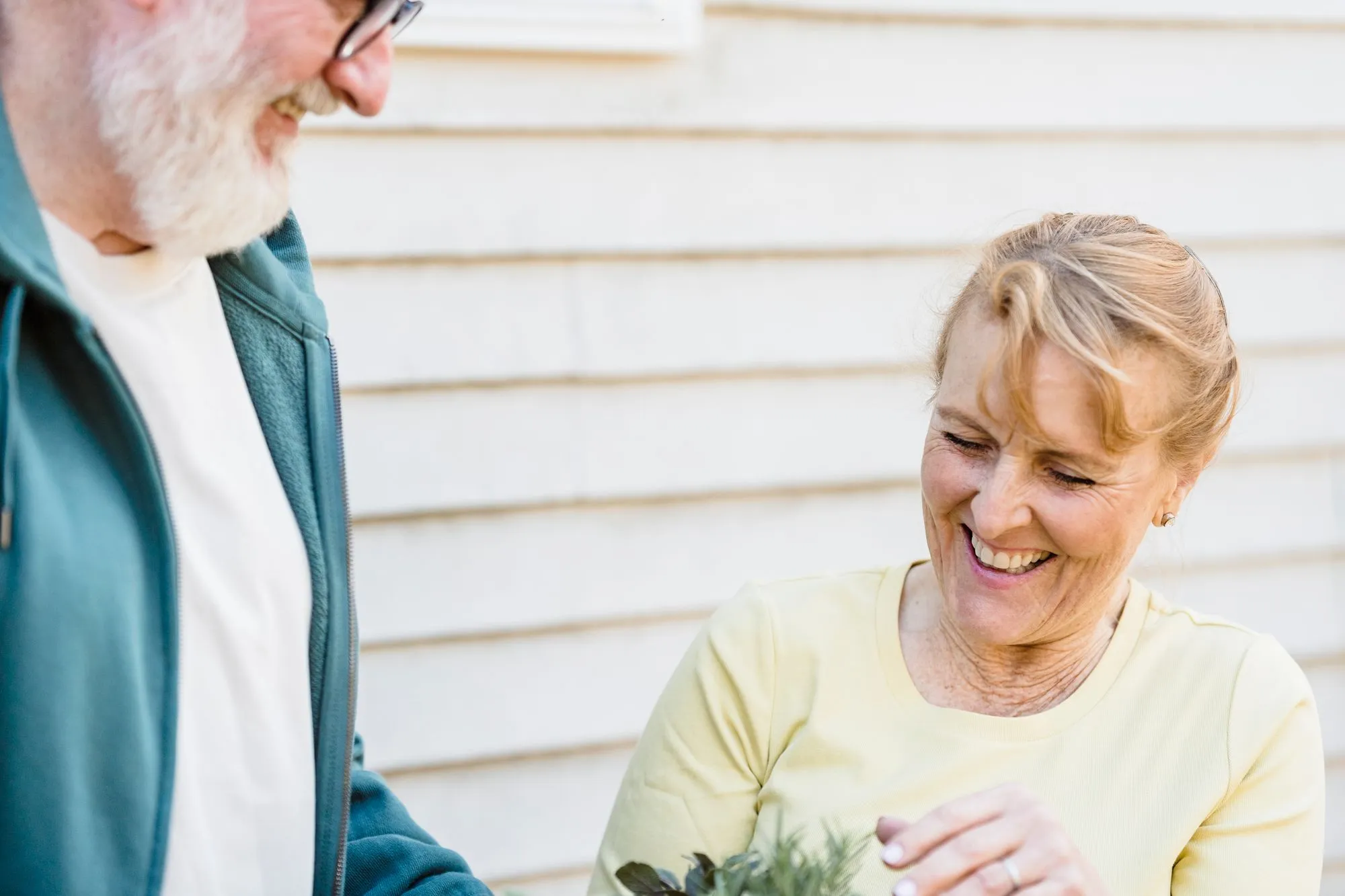 An older couple smiling as they tend to plants together